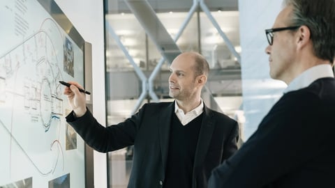 Professionals discussing strategy on a glass board, symbolising Yorktel and Kinly’s innovation-led consultancy and advisory expertise.